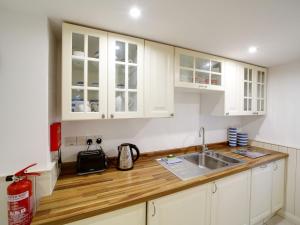 以撒港Bosuns Locker的厨房配有白色橱柜和木制台面