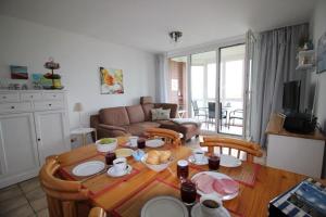 库克斯港Horizont-Wohnung-3的一间带木桌和椅子的客厅和一间厨房