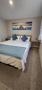PorchfieldBeautiful Caravan With Decking Wifi At Isle Of Wight, Sleeps 4 Ref 84047sv的卧室配有带蓝色枕头的大型白色床