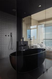 敖德萨Sea and Sky Apartment的一间带黑色浴缸的浴室和一间卧室