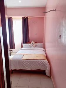 内罗毕Sislink Suites的粉红色客房内的一间卧室,配有一张床