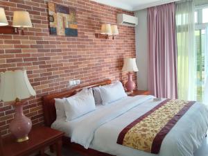 杜阿拉GRAND HOTEL CITY, Douala的一间卧室设有一张带砖墙的大床