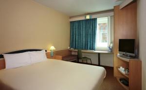 卡莱尔卡莱尔宜必思城市中心酒店的酒店客房配有一张床、一张书桌和一台电视。