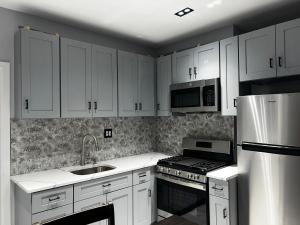 布鲁克林3 bedrooms in Modern Brooklyn home, Close to J train的厨房配有白色橱柜、炉灶和微波炉。