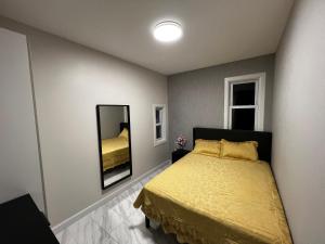 布鲁克林3 bedrooms in Modern Brooklyn home, Close to J train的一间卧室配有黄色的床和镜子