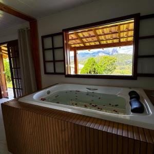 佩德拉阿祖尔Pousada Vista Pedra Azul的窗户客房内的大浴缸