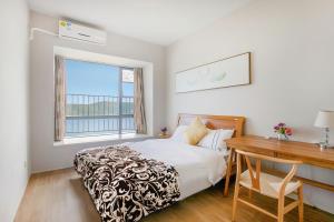 惠东小径湾海格酒店的一间卧室配有一张床、一张书桌和一个窗户。