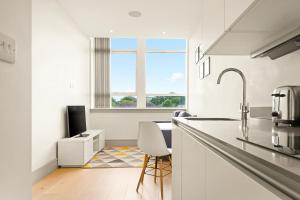 PinnerOne Bedroom Serviced Apartments in Harrow的白色的厨房配有水槽和椅子