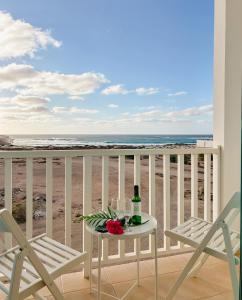 萨尔雷Papaya Apartments Boa Vista的海滩阳台的桌子和一瓶葡萄酒