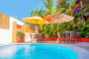 纳塔尔Garbos Soleil Hotel的游泳池畔的两把遮阳伞和桌椅