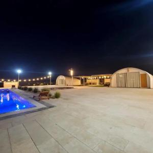 Al ḨamrānīyahDesert Breeze的夜间带游泳池的大型停车场