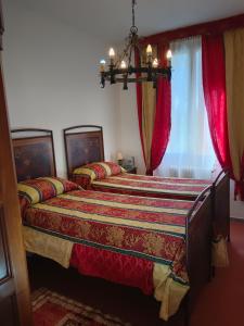 克雷斯佩拉诺La Maison Rouge的卧室内的两张床,配有红色窗帘