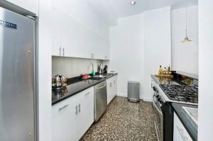 纽约Amazing 1300sf Loft By Union Sq的厨房配有白色橱柜和不锈钢冰箱