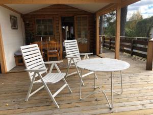 Ferienhaus in Västerrå mit Garten und Terrasse的甲板上配有两把白色椅子和一张桌子