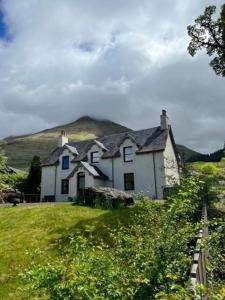克里安拉利Ferienhaus für 6 Personen ca 100 qm in Crianlarich, Schottland Loch Lomond and the Trossachs Nationalpark的一座白色的房子,后面有一座小山