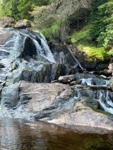 克里安拉利Ferienhaus für 6 Personen ca 100 qm in Crianlarich, Schottland Loch Lomond and the Trossachs Nationalpark的一条河,河里有瀑布和岩石