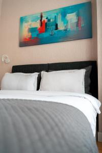 第比利斯Hotel Well Inn的一张带白色枕头的床和墙上的绘画