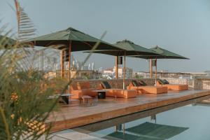 卡塔赫纳Osh Hotel Getsemani的游泳池旁的甲板上配有椅子和遮阳伞
