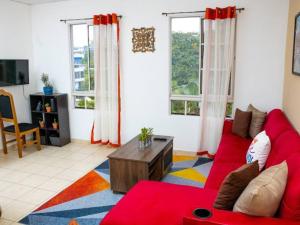 Antiguo CuscatlánCozy Two Bedroom Apartment Near The U.S. Embassy的一间带红色沙发和两扇窗户的客厅