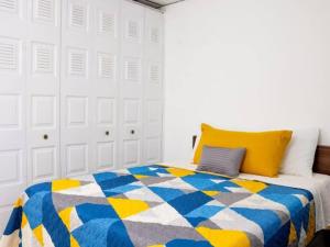 Antiguo CuscatlánCozy Two Bedroom Apartment Near The U.S. Embassy的一间卧室配有一张带蓝色和黄色被子的床