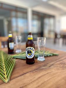 MsambweniYU Resort的木桌上的一瓶啤酒和一杯