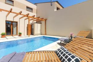 巴尔巴里加Ferienhaus mit Privatpool für 6 Personen ca 85 qm in Barbariga, Istrien Istrische Riviera的一座带2个木凳的游泳池,毗邻一座房子