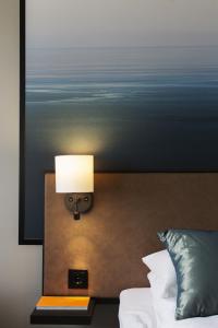 克里斯蒂安桑德豪华克里斯蒂安品质酒店的卧室配有一张床和墙上的灯。