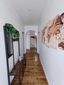 蓬蒂维Agréable maison neuve的走廊设有白色的墙壁、木地板和绘画作品