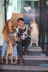 瓜达拉哈拉Art House Hostel Guadalajara的男人和女人坐在楼梯上,两只狗