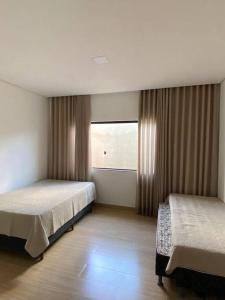 塞蒂拉瓜斯Sítio Gilmar2filhas的一间卧室设有两张床和窗户。