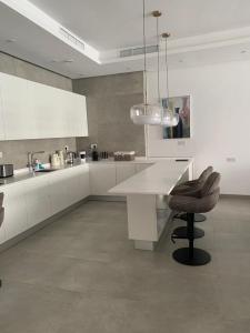 An Nāmī1718的厨房配有白色橱柜、桌子和椅子