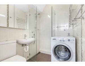 悉尼Beachside Paradise - Ocean Views, Central Position的白色的浴室设有洗衣机和水槽。
