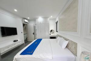 Royal Beach Villa Sonasea Vân Đồn Quảng Ninh的一间白色卧室,配有一张大床和一台电视