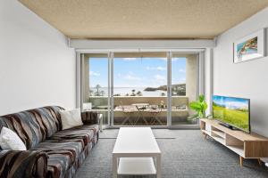 悉尼Apartment with Pool Access, a minute to the Beach的带沙发和大窗户的客厅