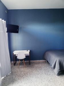 特古西加尔巴Habitación con balcón en una Mansión的蓝色卧室配有一张床和一张书桌