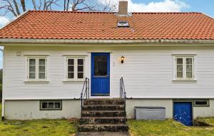 法尔松3 Bedroom Cozy Home In Farsund的白色的房子,有橙色的屋顶和蓝色的门
