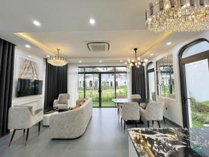 Royal Villa Vân Đồn Quảng Ninh的客厅配有吊灯和桌椅