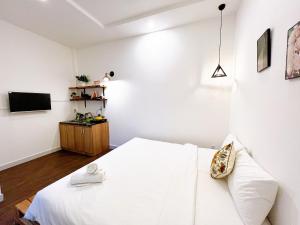 胡志明市Maison Bùi Viện的一间白色卧室,配有床和电视