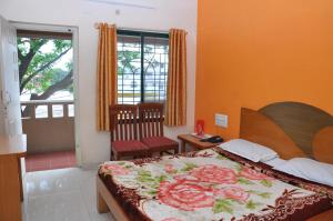 库斯哈尔纳加尔Vinayaka Deluxe Lodge的一间卧室配有一张带花毯的床