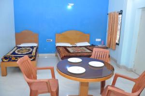 库斯哈尔纳加尔Vinayaka Deluxe Lodge的配有桌椅和床的房间