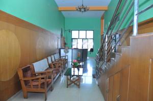 库斯哈尔纳加尔Vinayaka Deluxe Lodge的走廊上摆放着椅子和鲜花的桌子