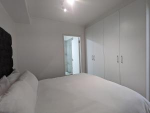 开普敦Modern Retreat in District Six的白色的卧室设有白色的床和窗户。
