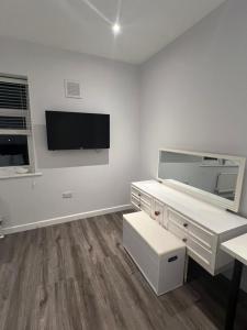 北安普敦Spencer bridge Rooms by AFL的白色的客房设有书桌和墙上的电视。