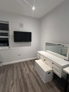 北安普敦Spencer bridge Rooms by AFL的白色的客房设有书桌和墙上的电视。