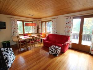 图拉彻霍赫Sunlit Cabin with Jacuzzi in Turracherhohe的客厅配有红色的沙发和桌子