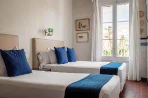 锡切斯梅迪姆浪漫酒店的带窗户的客房内的两张床