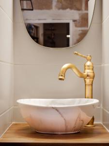 蒙彼利埃Le Chapeau Rouge - Centre Historique - Corum的一个带金色水龙头和镜子的盥洗盆