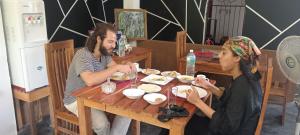 达瓦拉维Freedom Safari Cottage的坐在餐桌旁吃食物的男人和女人