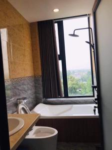 Thanh BìnhHotel Stylish Binh Long的带浴缸、卫生间和窗户的浴室