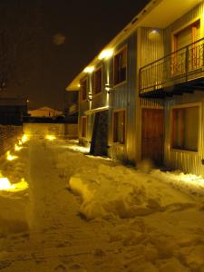 乌斯怀亚武库公寓的一座有灯光的建筑前的一条有雪覆盖的街道